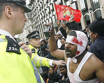 Pro-Tamil demonstrators face police after blocking a road in front of the Houses of Parliament in London
