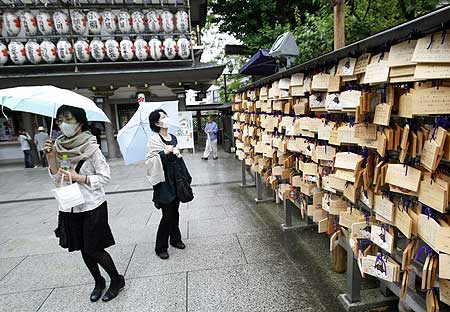Women wearing protective masks visit the Yushima Tenjin shrine in Tokyo on May 24