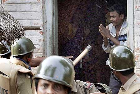 A villager begs a policeman to spare him from being arrested at Pirakata