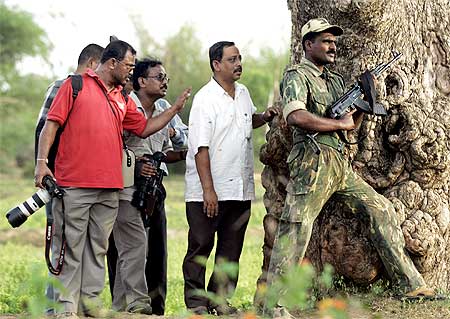 Media personnel and a police officer take cover behind a tree during a firefight between police and Maoists