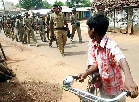 A boy watches police patrolling a road as they move towards Lalgarh