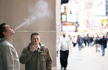 A pair of smokers stand outside of an office building at Times Square