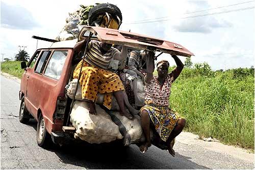 Residents ride in the back of a van as they flee with their farm products