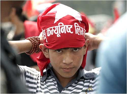 A boy puts on a 'Young Communist League' headband before taking part in an anti-government motorcycle rally in Kathmandu