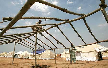 Men build a shelter, for those displaced by the military offensive in Swat, at a UN camp