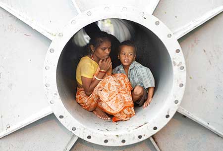 A homeless woman and her son take shelter inside a pipe to protect themselves from a storm in Kolkata
