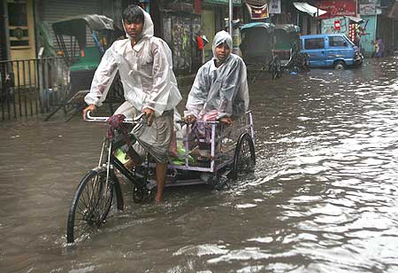Labourers wade through a flooded street in Kolkata