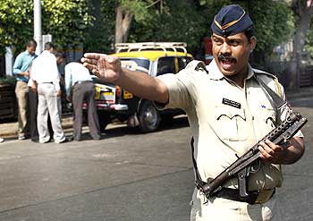 A policeman stands guard as members of a bomb detection squad examine baggage in Mumbai.