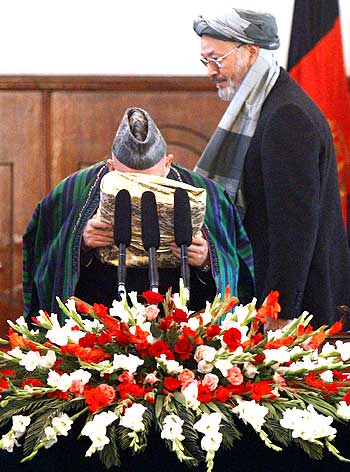 Afghanistan President Hamid Karzai kisses the Holy Koran after his inauguration as President as his Vice President Karim Khalili looks on