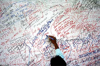 A visitor writes on a message board for the victims of 26/11 terror attack near the Taj Mahal Hotel.