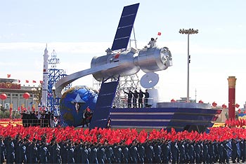 A float with a model featuring satellites is displayed during a  parade