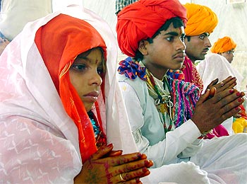 An eight-year-old bride sits besides her fourteen-year-old groom during their marriage ceremony