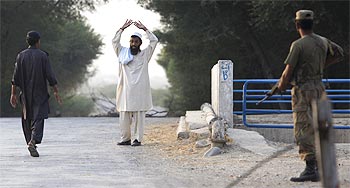 A cop approaches a man entering Dera Ismail Khan from South Waziristan by foot at a checkpost in Pakistan's South Waziristan