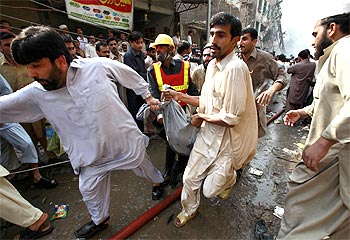 Rescuers carry the bodies of victims to ambulances at the blast site in Peshawar