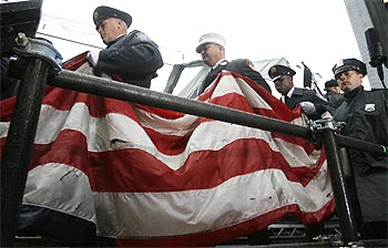 New York fire fighters carry a United States flag which survived the 9/11 attacks on the World Trade Center in New York