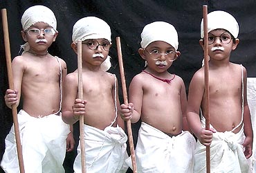 School children dressed as Mahatma Gandhi take part in a cultural programme
