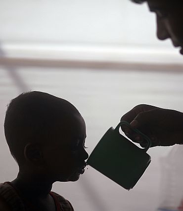 A father feeds his child Riayd, who is suffering from diarrhoea, with oral saline at the International Centre for Diarrhoeal Disease and Research in Dhaka