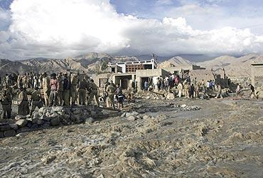 Soldiers and rescuers search for survivors near an overflowing stream