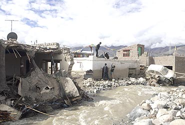 Victims retrieve their belongings from their partially damaged house in Leh