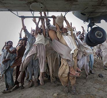 Marooned flood victims looking to escape grab the side bars of a hovering Army helicopter which arrived to distribute food supplies in the Muzaffargarh district of Pakistan's Punjab province.