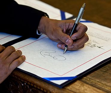 President Barack Obama signs a bill in the Oval Office