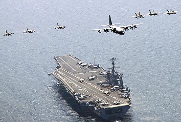 A US C-130 Hercules aircraft leads a formation of fighter jets over aircraft carrier USS George Washington in the East Sea of Korea in July, 2010