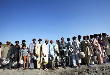 Flood-hit people queue up for food handouts in Sukkur, Pakistan