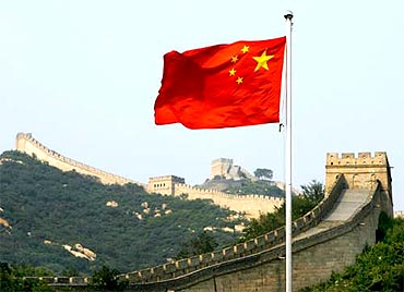 A Chinese flag flutters against the backdrop of the Great Wall of China
