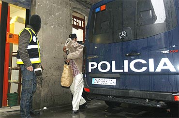 Police officers take an arrested man into a car after a police operation in Barcelona.The Spanish police have arrested at least 11 people in Barcelona and Valencia suspected of forging documents for Al Qaeda