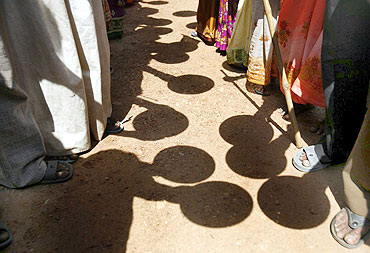 Villagers hold empty plates as they stand in front of a government office to protest against corruption