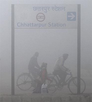 People ride bicycles on a foggy morning in New Delhi