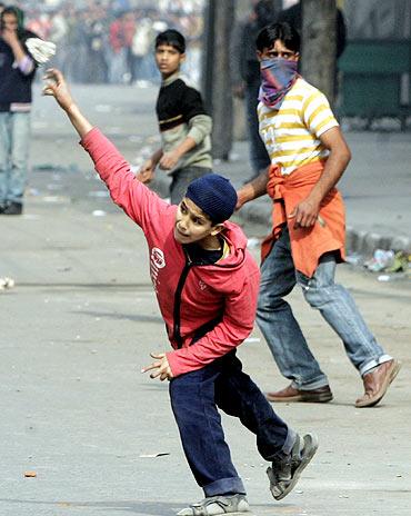 A Kashmiri protester throws a stone towards a policeman during a protest in Srinagar