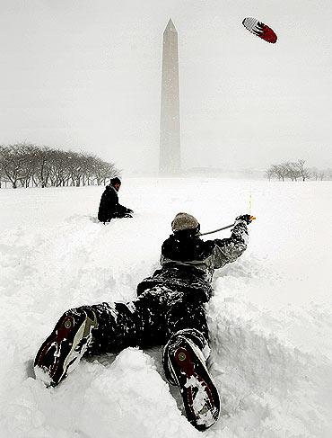 A woman kitesurfs near the Washington Monument during a snow squall on the National Mall in Washington