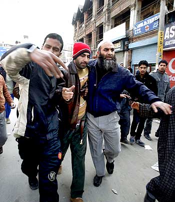 Kashmiri people help an injured man during a gunbattle between soldiers and separatists in Srinagar