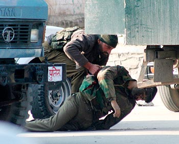 A policeman lifts the body of a slain colleague during the encounter on Wednesday