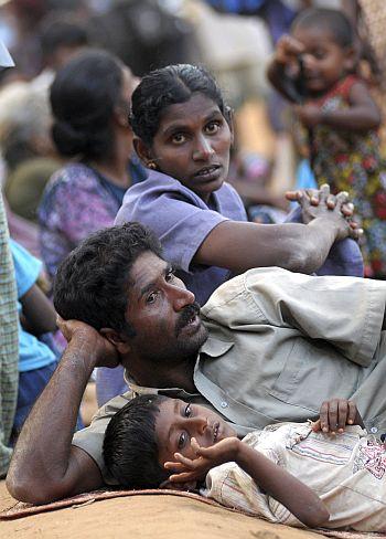 Ethnic Tamil civilians wait to go to a camp for internally displaced people after being checked by the military in Vishvamadu