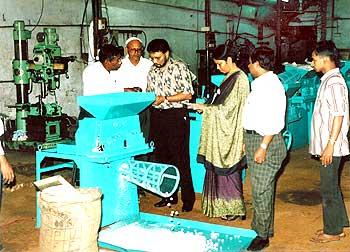 Dr Roy, accompanied by IFDC staff, observes a demonstration of a urea briquette machine at SIMS manufacturing company in Bangladesh