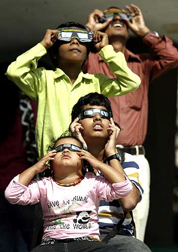 People use solar viewers to view an annular solar eclipse at the Nehru planetarium in Mumbai