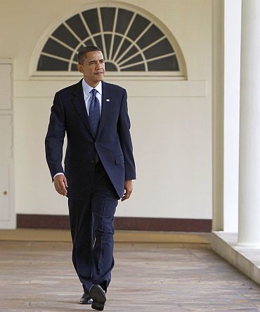 Obama walks on the West Wing Colonnade towards the Oval Office