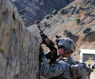 A US Army gunner peers over a canal wall during a patrol along the Kunar River in Kunar province