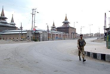 A security personnel walks through the deserted streets of Srinagar as curfew was clamped in few parts of the city on Tuesday