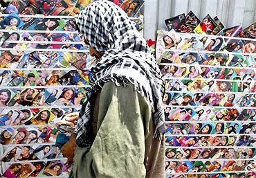 An Afghan woman looks at picture postcards of Bollywood stars