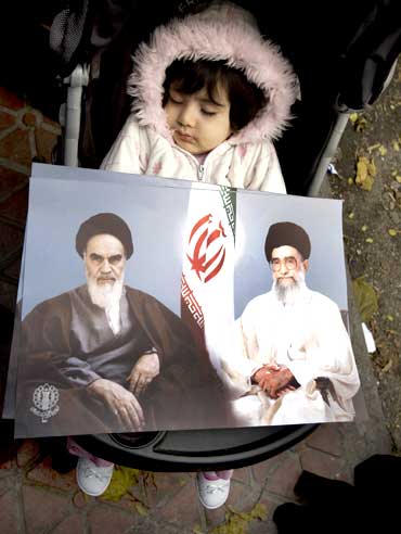 Placards with images of Islamic leaders Khomeini and Khamenei are placed on a sleeping girl