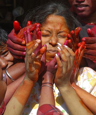 People smear the face of a woman with coloured powder during Holi in Allahabad
