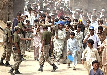 Soldiers try to control a mob of internally displaced men at a camp in Swat