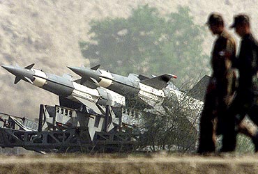 Soldiers walk past missiles positioned close to the border with Pakistan