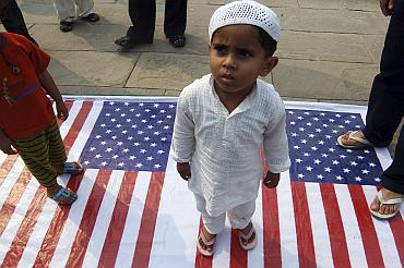 A child stands on a US flag during a protest in Lucknow