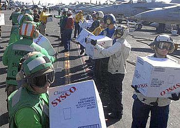 Sailors aboard the aircraft carrier USS Ronald Reagan (CVN 76) take boxes of supplies off a C-2A Greyhound from Fleet Logistics Combat Support Squadron (VRC) 30 to be transferred to the Carnival cruise ship