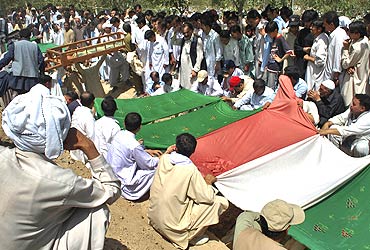 Locals cover the graves of victims killed during a terror attack on a Shia procession in Quetta