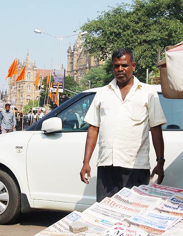 Newspaper vendor Anand Sawant outside CST (in the background)